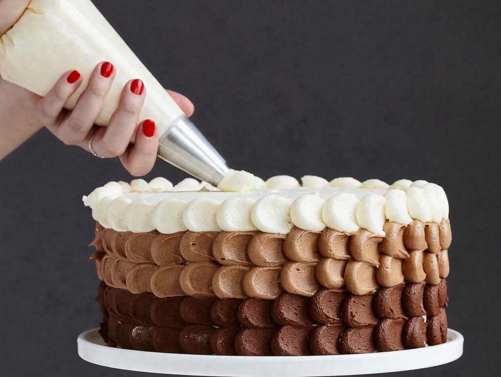woman's hand piping frosting on a cake