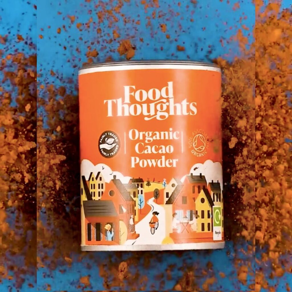 Dramatic image of a Food Thoughts organic cacao powder tub with cacao powder exploding at the background