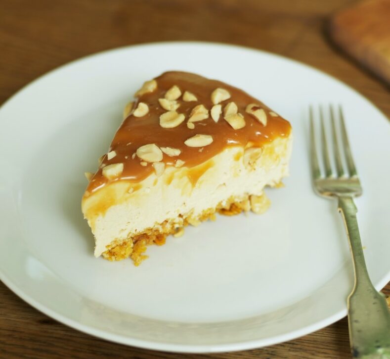 slice of caramelised white chocolate cheesecake with peanuts on plate