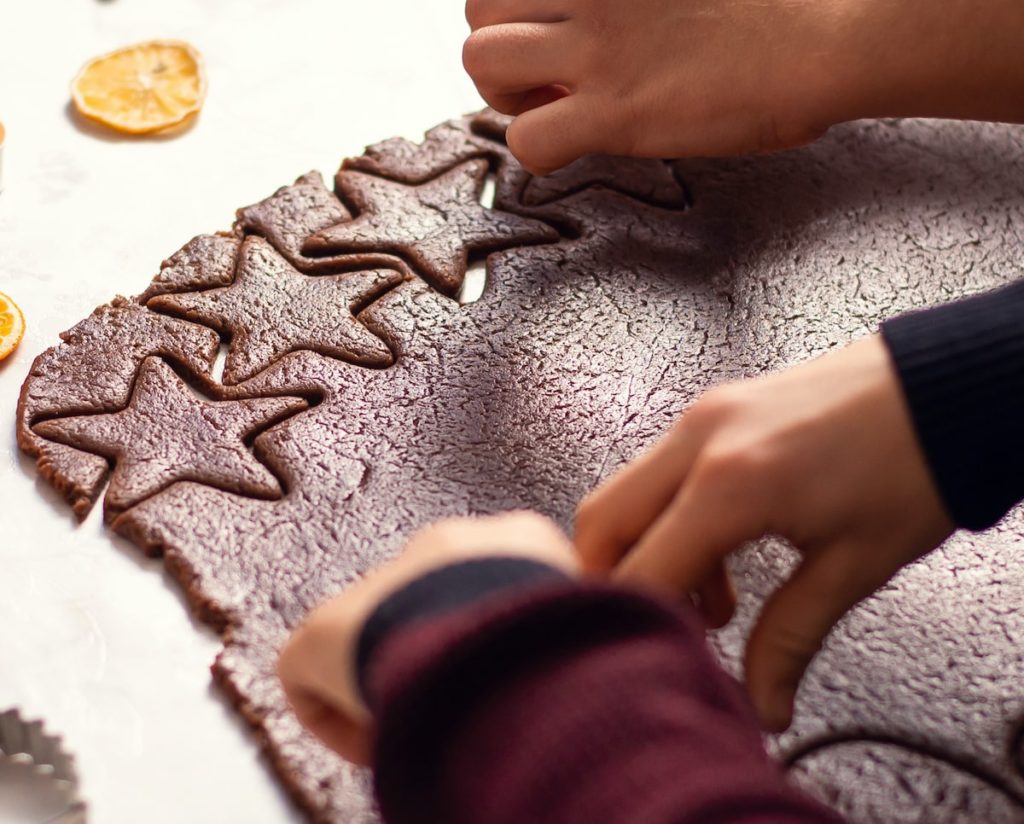hands shown cutting in star shape cacao gingerbread biscuits