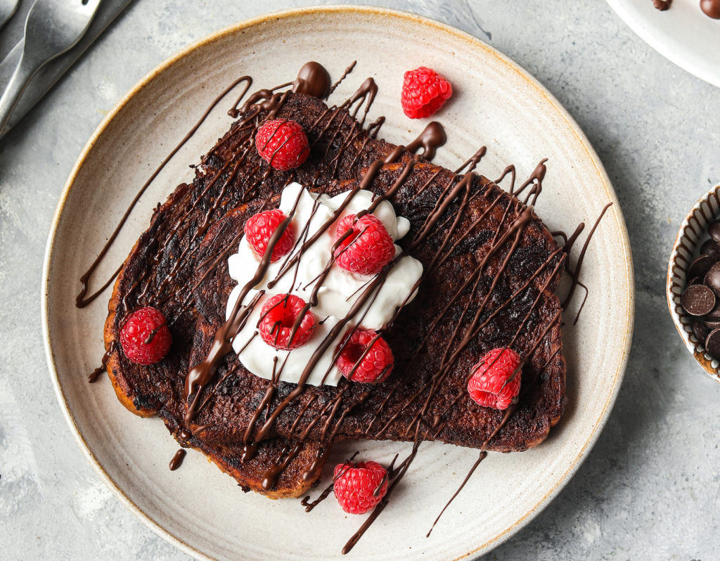 chocolate french toast on plate with yoghurt and raspberries