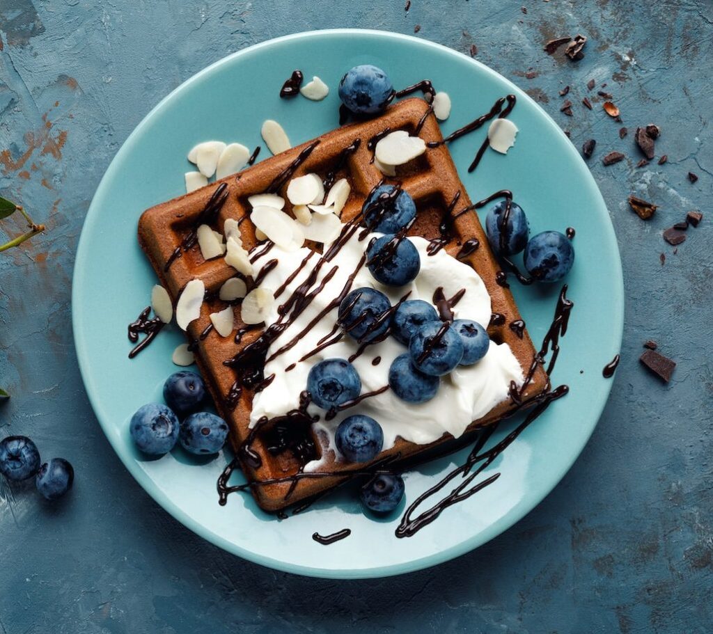 chocolate waffle with cream and blackberries on a plate