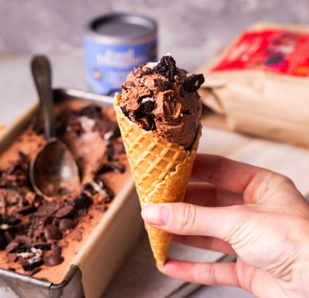 Hand holding milk chocolate Oreo ice cream in a cone