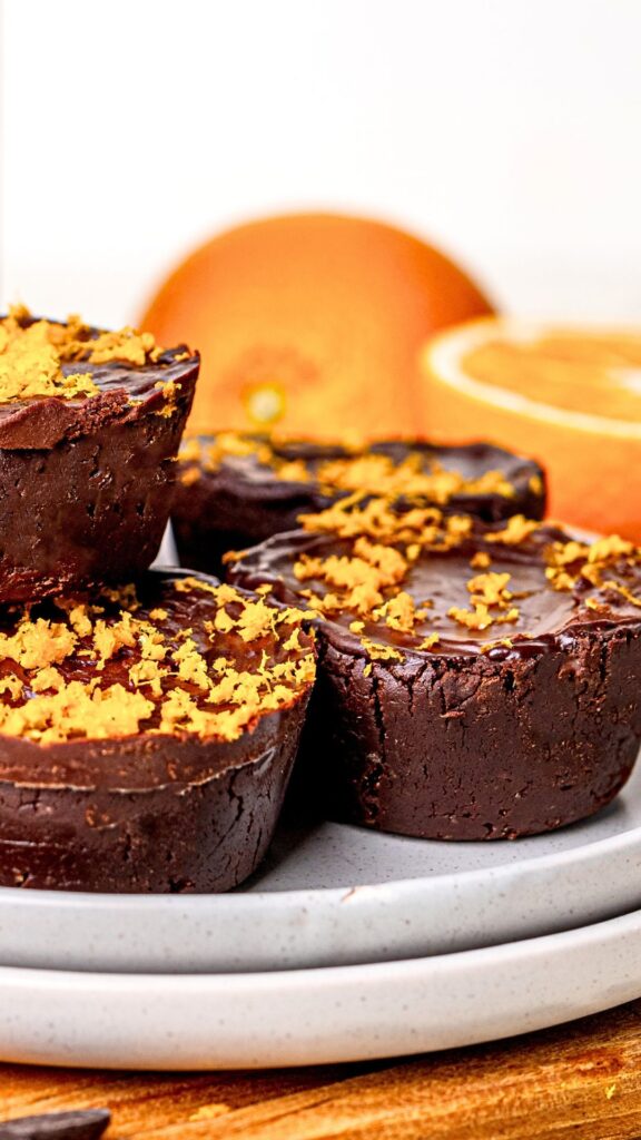 Chocolate orange brownie cups stacked on a plate, full of indulgence.